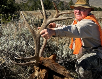 A happy  hunter posing with his bull elk
